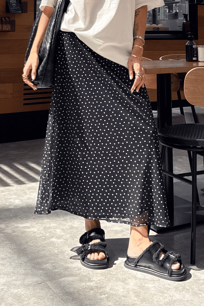 Saia midi de tule com estampa poá, leve e fluida, com forro embutido e cós elástico confortável.