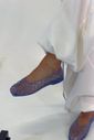sapatilha-feminina-azul-gummy Detalhe do pé calçado com a Sapatilha Feminina Azul - Gummy em movimento, com calça branca fluida e leve corrente dourada no tornozelo.