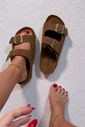 santorine-flatform-unissex-bege Papete feminina marrom com fivelas douradas usada nos pés