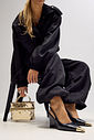 Slingback Naomi Preto Editorial Modelo segurando bolsa metalizada dourada enquanto usa slingback feminino Naomi preto com salto anabela e bico metálico dourado em destaque.