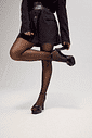Sandália Meia Pata Lulu Preta Feminina Modelo em pé usando a sandália meia pata Lulu preta, segurando um dos saltos para destacar o design da meia pata, o salto bloco e a tira ajustável no tornozelo.