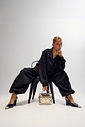 Slingback Naomi Preto com Look Modelo usando slingback feminino Naomi preto com salto anabela e bico metálico dourado, combinado com look preto e bolsa metalizada dourada.