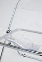 gummy-tamanco-feminino-transparente-salto-baixo Tamanco Feminino Flip Flop Gummy transparente em PVC sobre cadeira metálica, vista superior destacando as tiras e o bico quadrado