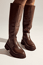 zuna-bota-feminina-cano-longo-tratorada-marrom Detalhe das pernas com bota feminina cano longo tratorada marrom ZUNA