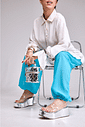 tamanco-flatform-feminino-tira-vinil-prata Adele - Tamanco Flatform Feminina Tira Vinil Prata nos pés da modelo sentada, segurando bolsa prata