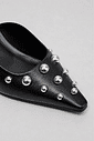 Detalhes das Aplicações do Mule Zara Close frontal do mule feminino Zara preto destacando o acabamento do material, o bico fino e as aplicações metálicas prateadas em diferentes tamanhos.
