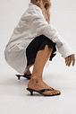 gummy-tamanco-feminino-salto-baixo-translucido-preto Tamanco Feminino Flip Flop Gummy preto nos pés da modelo com calça branca em look casual