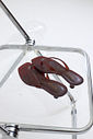 gummy-tamanco-feminino-transparente-salto-baixo-marrom Par de Tamanco Feminino Flip Flop Gummy marrom em PVC translúcido sobre cadeira transparente, vista superior