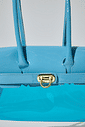 gummy-bolsa-feminina-transparente-verniz-azul-claro Detalhe frontal da Bolsa Feminina Transparente Verniz Gummy azul claro com acabamento em verniz e fecho metálico dourado.