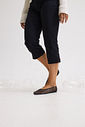 sapatilha-feminina-preto-gummy Closeup dos pés calçados com a Sapatilha Feminina Preto - Gummy em movimento, com calça preta cropped e tricô creme, cenário com bolhas de sabão no chão.