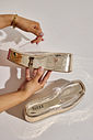 tamanco-flatform-feminino-tira-vinil-dourado-adele Mão segurando o Adele - Tamanco Flatform Feminina Tira Vinil Dourado, mostrando o solado e a marca Use Hitzz