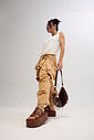 bangkok-tamanco-feminino-camel Modelo em pé com o Tamanco bangkok e bolsa Kuromi preta