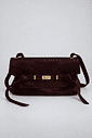 bolsa-feminina-ombro-marrom-vick Bolsa de couro marrom vista de frente, alça ajustável, fecho dourado e tiras laterais soltas, fundo cinza claro.