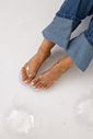 gummy-tamanco-feminino-transparente-salto-baixo Tamanco Feminino Flip Flop Gummy transparente nos pés da modelo com calça jeans, vista de cima