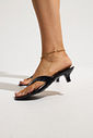 gummy-tamanco-feminino-salto-baixo-translucido-preto Tamanco Feminino Flip Flop Gummy preto em PVC nos pés da modelo, destacando as tiras e o salto baixo