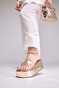 tamanco-flatform-feminino-tira-vinil-dourado-adele Adele - Tamanco Flatform Feminina Tira Vinil Dourado no pé da modelo com calça branca, segurando bolsa dourada
