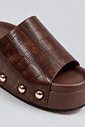 tamanco-feminino-flatform-croco-marrom-lara Close da textura croco marrom e tachas douradas do tamanco flatform Lara