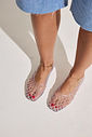 sapatilha-feminina-transparente-gummy Closeup dos pés calçados com a Sapatilha Feminina Transparente - Gummy em movimento, mostrando o esmalte vermelho por trás da trama vazada.