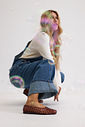 sapatilha-feminina-marrom-gummy Modelo agachada usando a Sapatilha Feminina Marrom - Gummy com tricô canelado creme e jeans wide leg índigo, composição editorial com efeito de luz e tornozeleira dourada.
