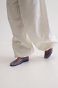 sapatilha-feminina-azul-gummy Modelo caminhando com calça wide leg branca, usando o par da Sapatilha Feminina Azul - Gummy, cenário minimalista de estúdio.
