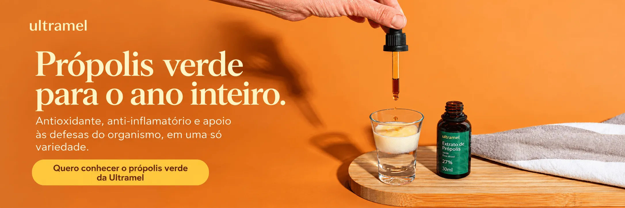 Três frascos de extrato de própolis da marca Ultramel — nas versões base álcool 30ml, vermelha 20ml e aquosa verde 11% 30ml — dispostos sobre uma superfície de juta, com uma mão segurando um conta-gotas cheio de extrato escuro sobre uma xícara de vidro com líquido âmbar.