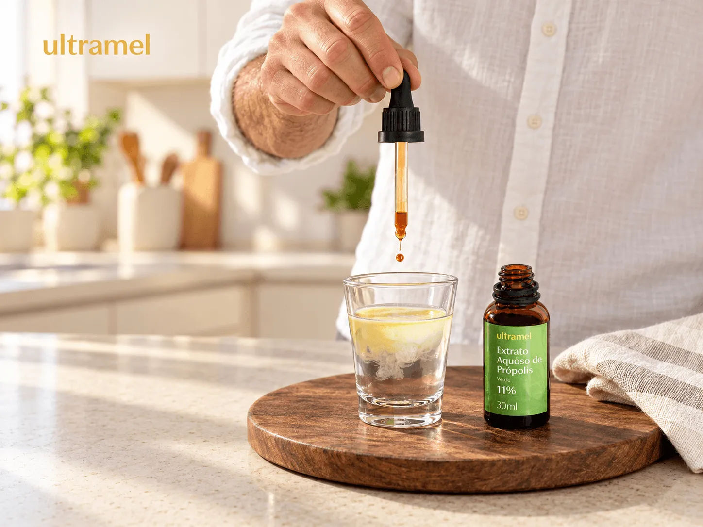 Homem gotejando Extrato Aquoso de Própolis Verde Ultramel 11% em um copo com água, sobre uma tábua de madeira em uma cozinha iluminada. O frasco âmbar de 30ml do produto está posicionado ao lado do copo.