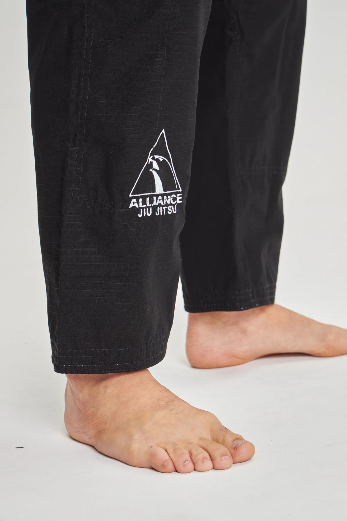 Close da calça preta com bordado Alliance — foto 64060